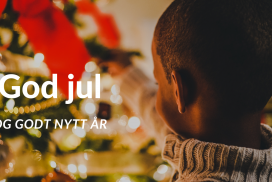 God jul i tekst over juletre som en melaninrik gutt med kort, svart hår står og pynter (med bakhodet mot kamera).